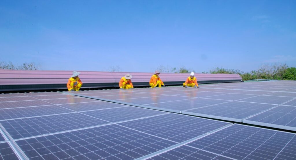 Installateur posant des panneaux solaires photovoltaïques sur toiture maison individuelle