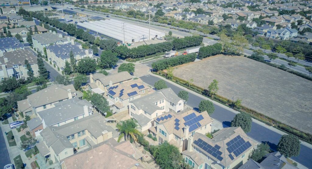 Technicien nettoyant des panneaux solaires sur un toit en pente avec brosse télescopique
