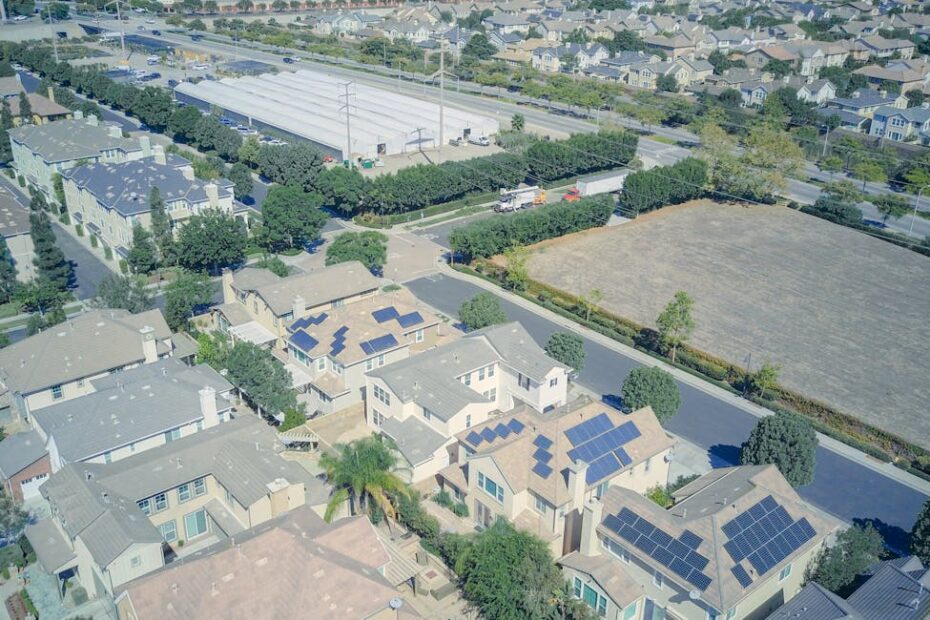 Technicien nettoyant des panneaux solaires sur un toit en pente avec brosse télescopique