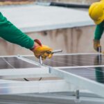 Technicien posant des panneaux solaires photovoltaïques sur toiture résidentielle ensoleillée