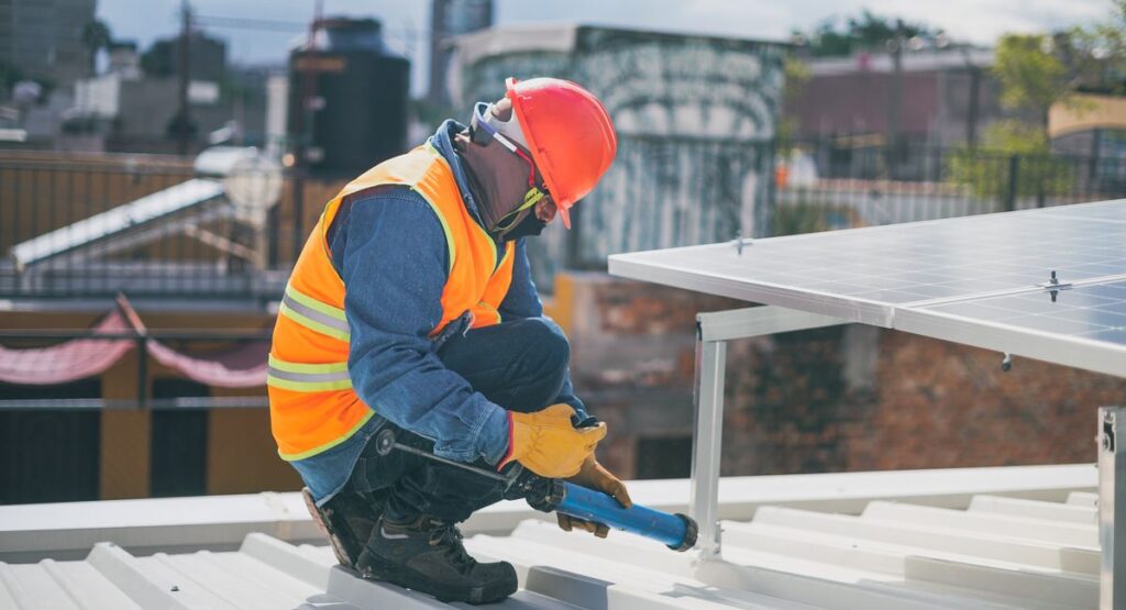Technicien installant des panneaux solaires sur toiture maison individuelle